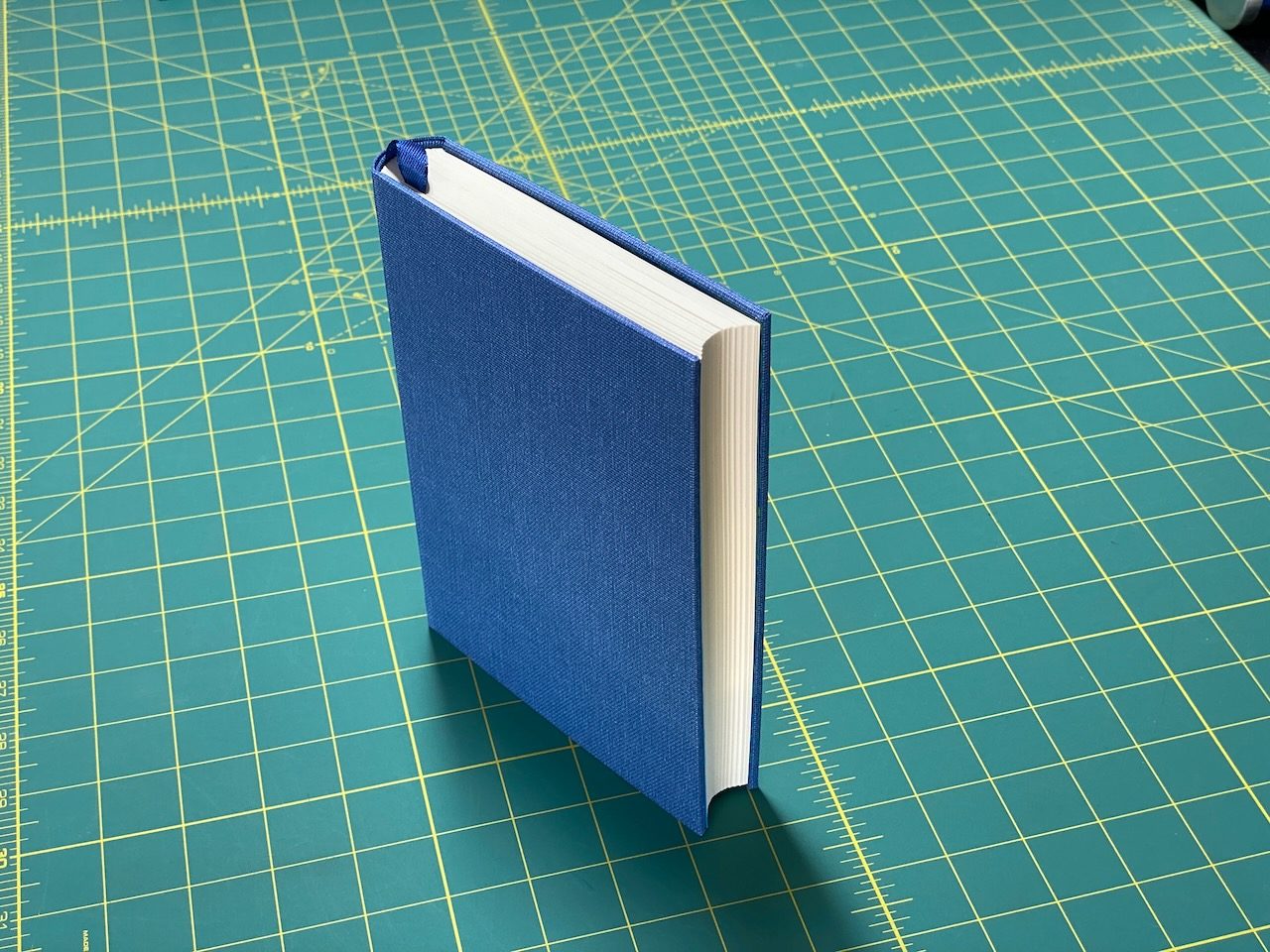 Blue cloth-covered book standing on a green cutting mat