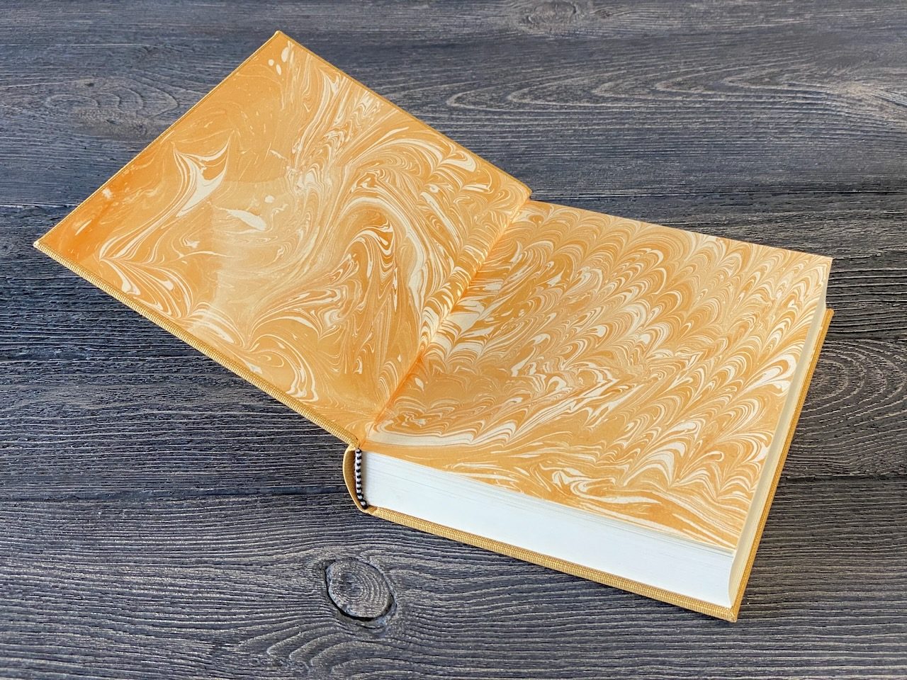 Golden marbled paper opened across a workbench beside a book