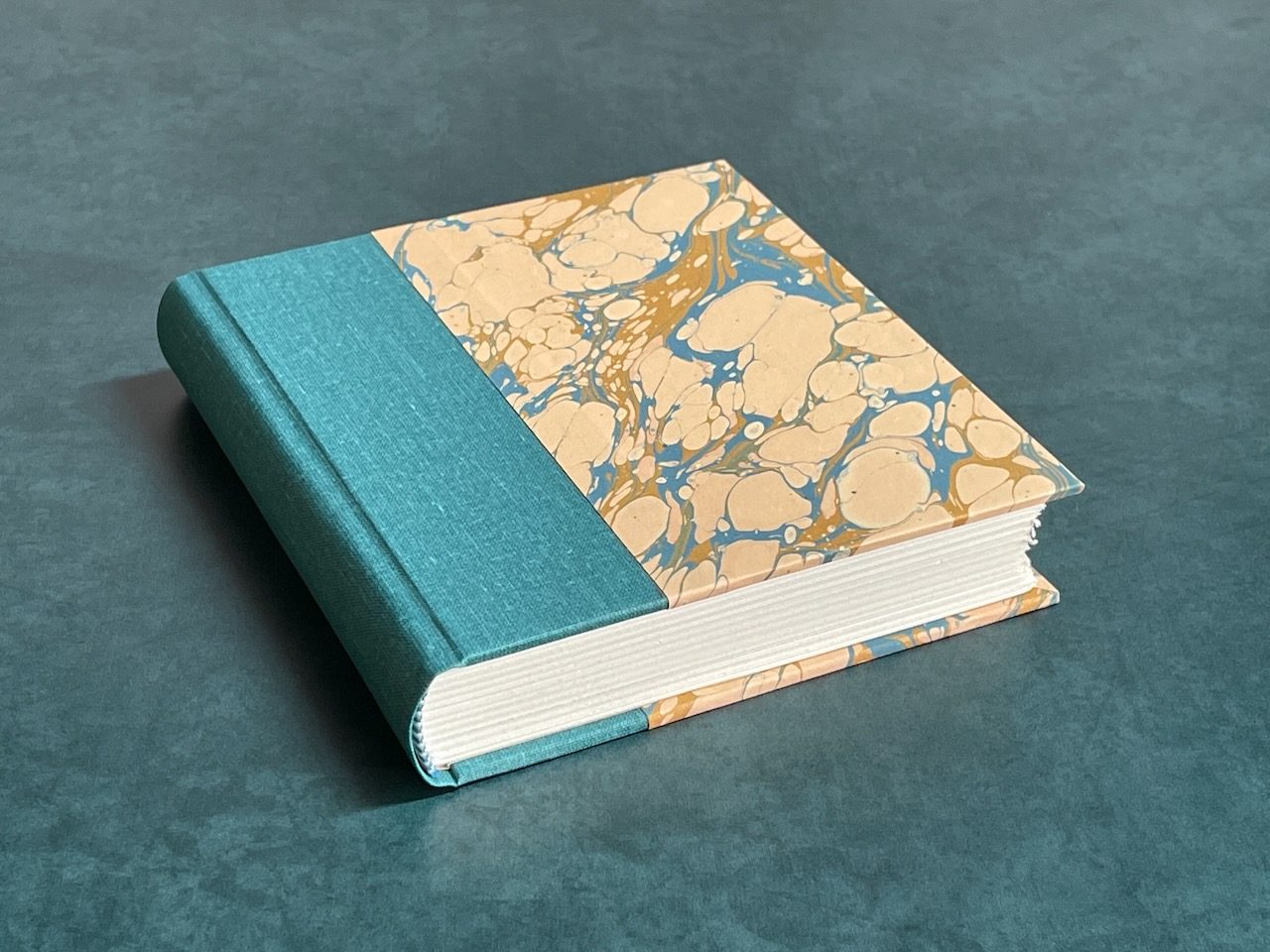 Teal cloth binding with warm marbled paper boards